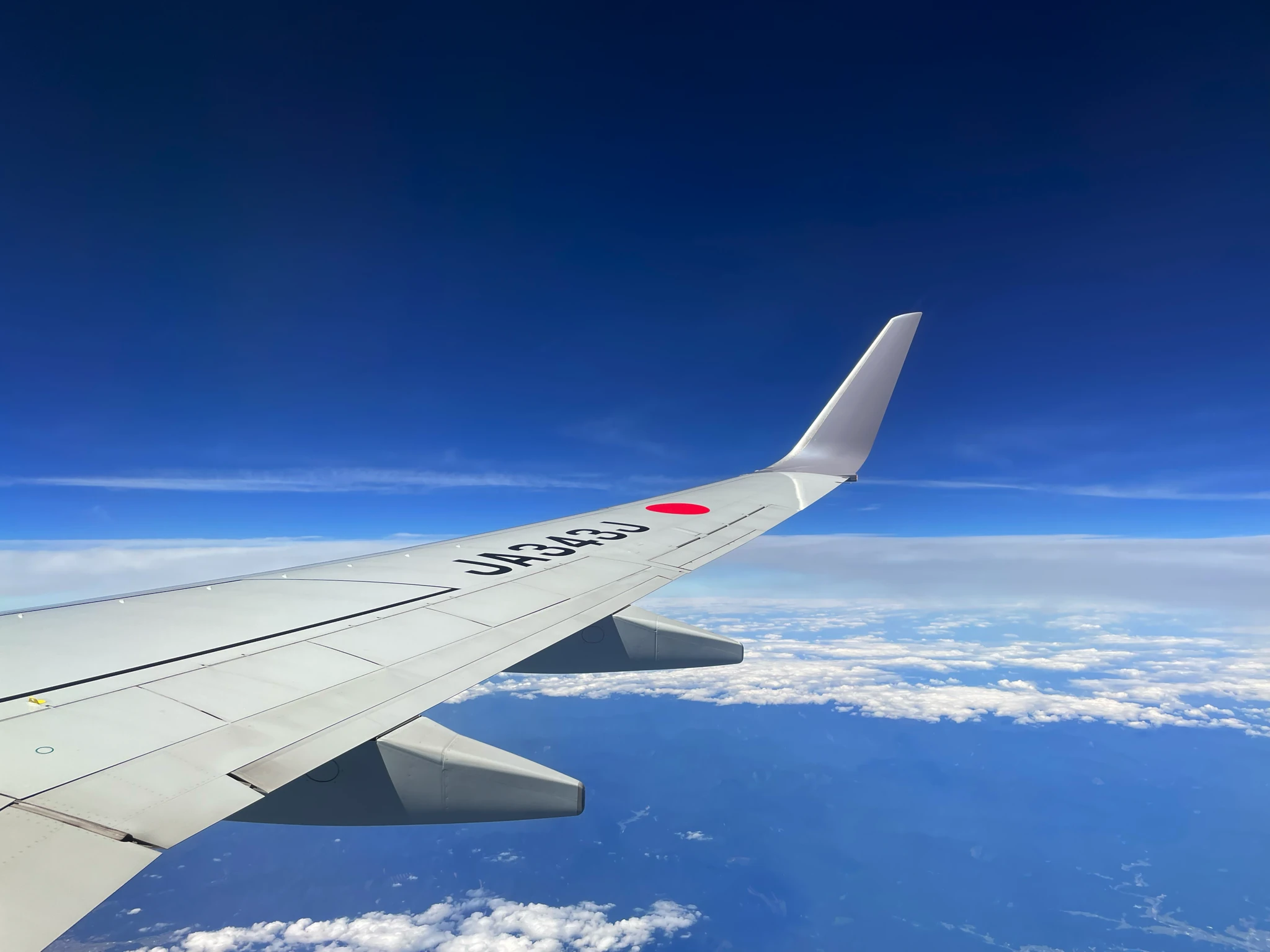 本社所在地のお知らせに掲載された航空機の翼と空の写真
